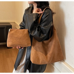 Detail of a brown frosted suede tote bag set with matching pouch on a shoulder