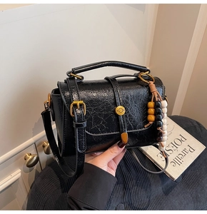 Macro view of vintage black cracked leather texture and golden metal lock on small bag