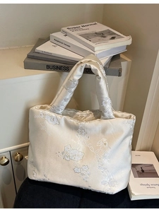 Elegant off-white satin tote bag featuring intricate floral embroidery and wide handles