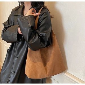 Retro brown oversized hobo tote bag in suede texture worn over a black leather jacket