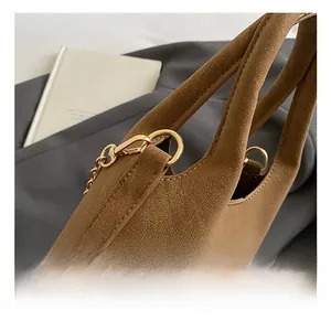 Dettaglio della borsa in pelle marrone testurizzata con catena dorata e ganci in metallo