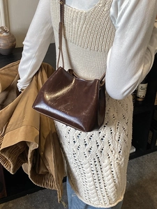 Sac seau rétro en cuir brillant marron foncé avec logo embossé porté par un mannequin