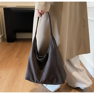 Close-up of a large dark brown matte leather hobo bag worn with a stylish trench coat