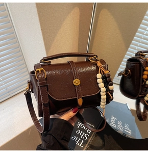 Detailed shot of dark brown Boston bag with glossy finish and retro beaded charm