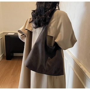 Macro detail of the dark grey matte suede tote bag shown on a model for size and drape