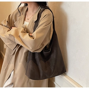 Detail of a large matte brown leather tote bag with wide straps for minimalist daily commute