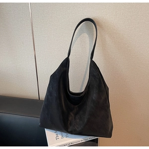 Detail of black matte Hobo shoulder bag with central seam and wide strap on leather sofa