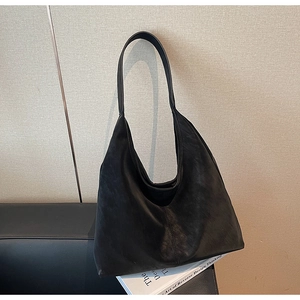 Detail of a large black matte leather hobo bag with vertical stitching and wide shoulder strap