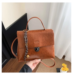 Detail einer dunkelbraunen PU-Leder Handtasche mit Fransenquaste und Schnallenverschluss