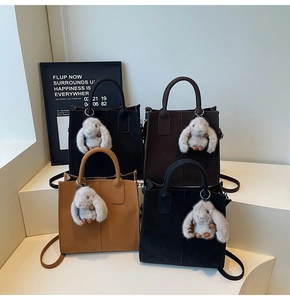 Close-up of four minimalist tote bags in brown and black with rabbit plush charms