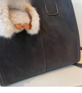 Close-up of a dark brown vintage suede tote bag featuring soft texture and plush charm