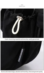 Detail view of black nylon crossbody bag with white drawstring and metal toggle