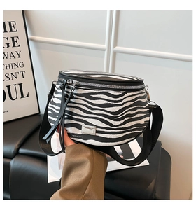 Detail der Crossbody-Tasche mit Zebramuster, Silber-Reißverschluss und Logo-Plakette