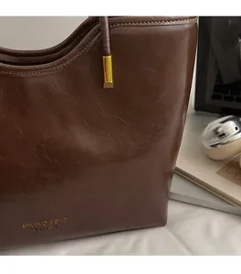 Detailed close-up of brown oiled leather texture with golden brand logo and metal hardware