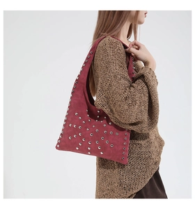 Detailed view of burgundy suede shoulder bag with silver studs and premium metal texture