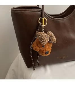 Detail of teddy dog plush bag charm with brown plaid bow and golden metal hook