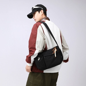 Detail of durable black nylon crossbody bag featuring textured fabric and beaded zipper pulls