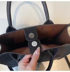 Detail view of magnetic metal snap closure on fashion handbag with contrast lining