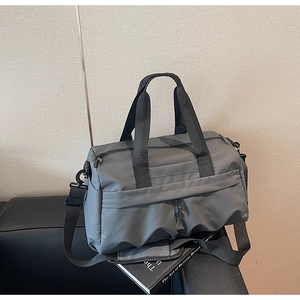 Détail du sac de voyage gris avec poches zippées et bandoulière sur un banc