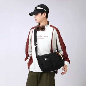 Detail of black waterproof nylon crossbody bag with wood bead accessory and zip pocket