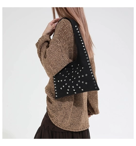 Detail of silver rivets on black suede shoulder bag worn with a brown knit sweater