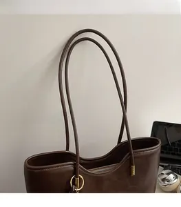 Detail of slim leather shoulder straps and gold ring hardware on a brown tote bag