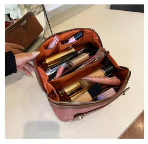 Detail of suede vanity bag with three large compartments and golden rivet studs