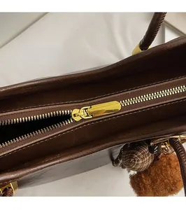 Close-up of smooth gold metal zipper and faux fur pom-pom on vintage tote bag