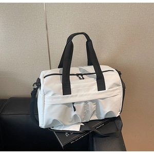 Détail d'un sac de voyage en toile blanche avec poignée noire et bandoulière réglable