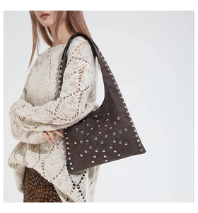 Detail of dark brown suede hobo bag with silver rivets worn by a model in leopard skirt