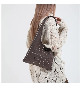 Detailed view of dark brown suede shoulder bag with silver studs on female model