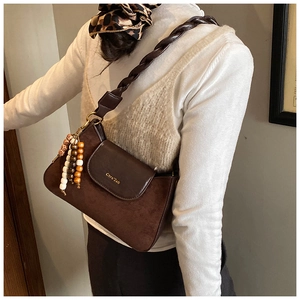 Detail of retro dark brown suede shoulder bag with woven strap and bead charms