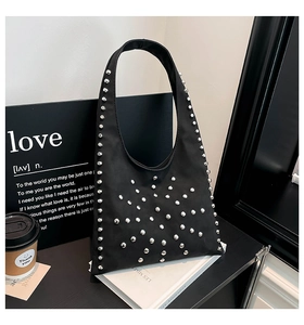 Close-up of black nylon underarm bag with silver stud rivets on minimalist white books