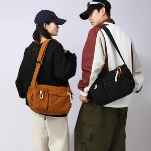 Models wearing large black and orange crossbody tote bags with ethnic beaded charms