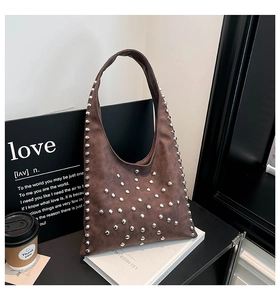 Macro detail of brown vintage hobo bag featuring polished silver rivets and matte texture