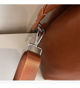 Detail of silver metal hardware and brown fabric shoulder strap on pebble leather tote