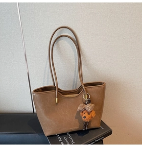 Detailed view of brown oil wax leather tote bag with a cute teddy bear plush charm