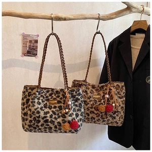 Detail of leopard print plush tote bags with braided leather handles and pompom charms