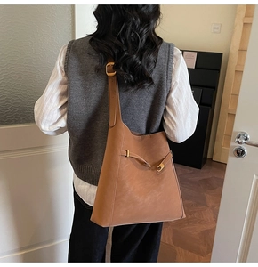 Brown leather hobo bag with adjustable strap shown on model in modern interior setting