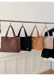 Detail view of four colorful suede tote bags with circular embossed logos and clean edges