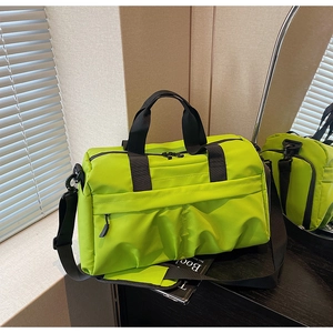 Détail du sac de voyage en nylon vert néon avec poignées noires et bandoulière réglable