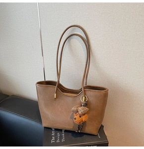 Detail of vintage brown oil wax leather tote bag with a cute plush dog pendant
