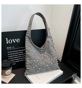 Detailed view of silver rivets on grey suede hobo bag styled with a coffee cup