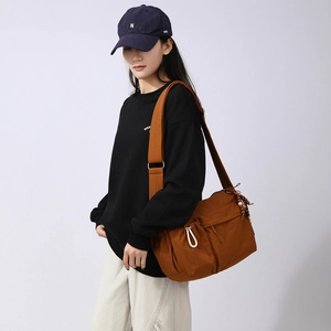 Nylon crossbody bag in caramel with side drawstring pocket shown on a model