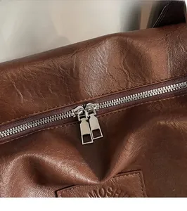 Détail de la double fermeture éclair argentée sur un grand sac cabas en cuir marron