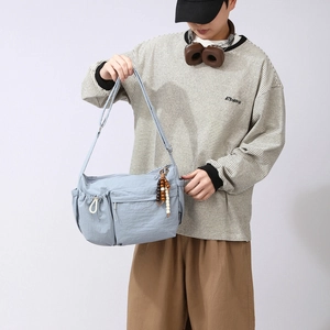 Detailed close-up of light blue nylon crossbody bag with functional multi-pocket design