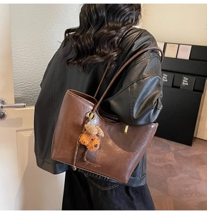 Detail of vintage brown leather tote bag showing smooth texture and bear charm
