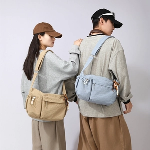 Close-up of lightweight nylon crossbody bag featuring multi-zipper compartments and wide straps