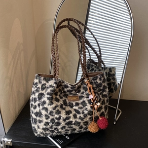 Close-up of leopard print faux fur tote with leather tag and decorative plush pompom