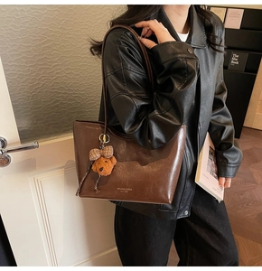 Detail of dark brown oil wax leather tote bag with cute plush bear charm on shoulder